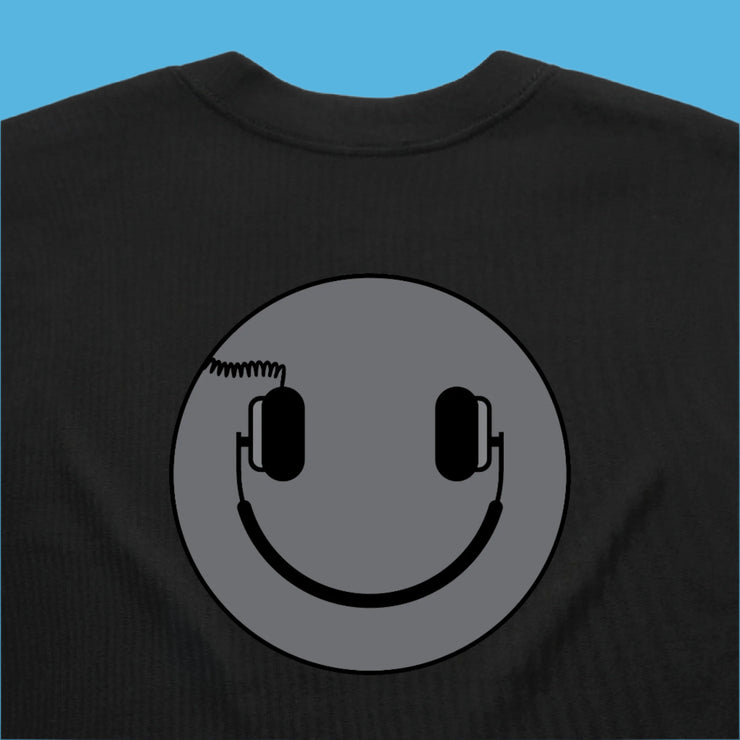 Black sweatshirt with a smiley face design featuring headphones on a gray background.